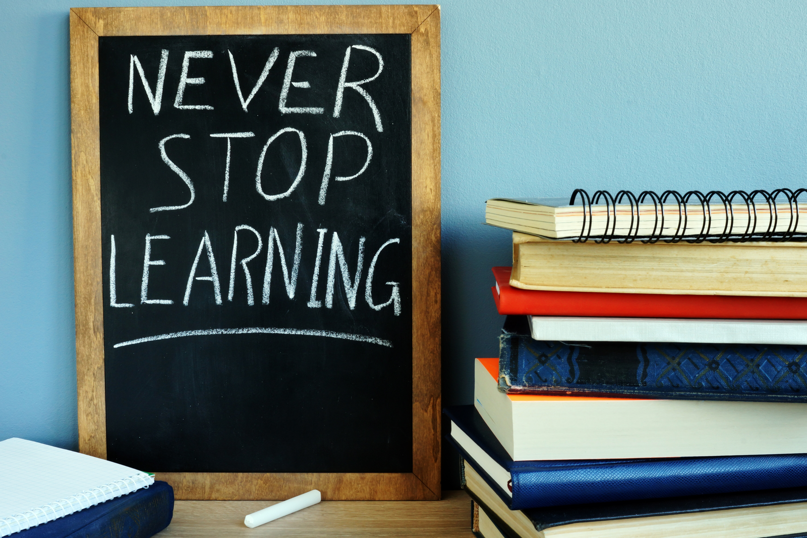 Never stop learning chalkboard beside a stack of books