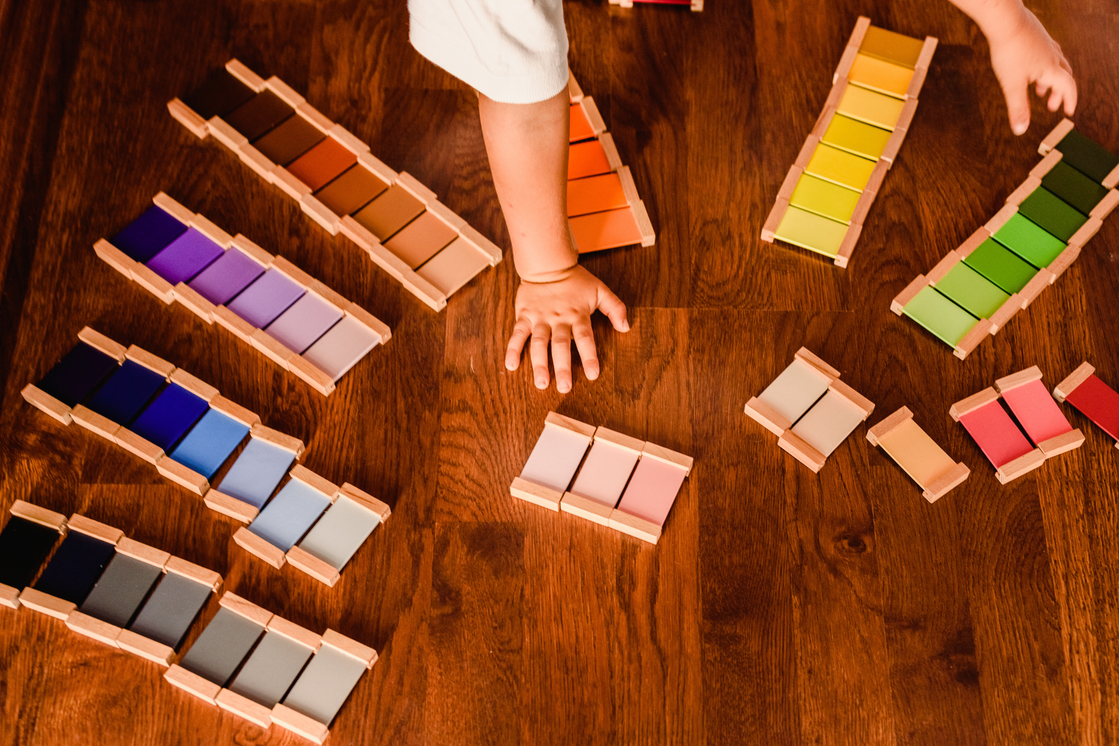 Child organizing Montessori color tablets on the floor