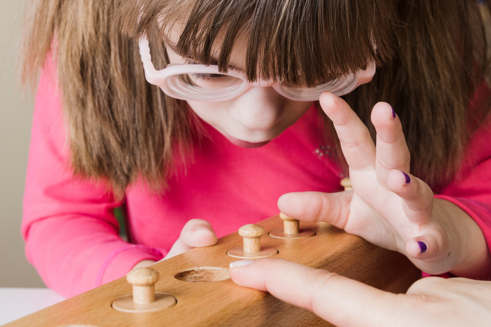 Educator guiding a child through Montessori cylinder block work