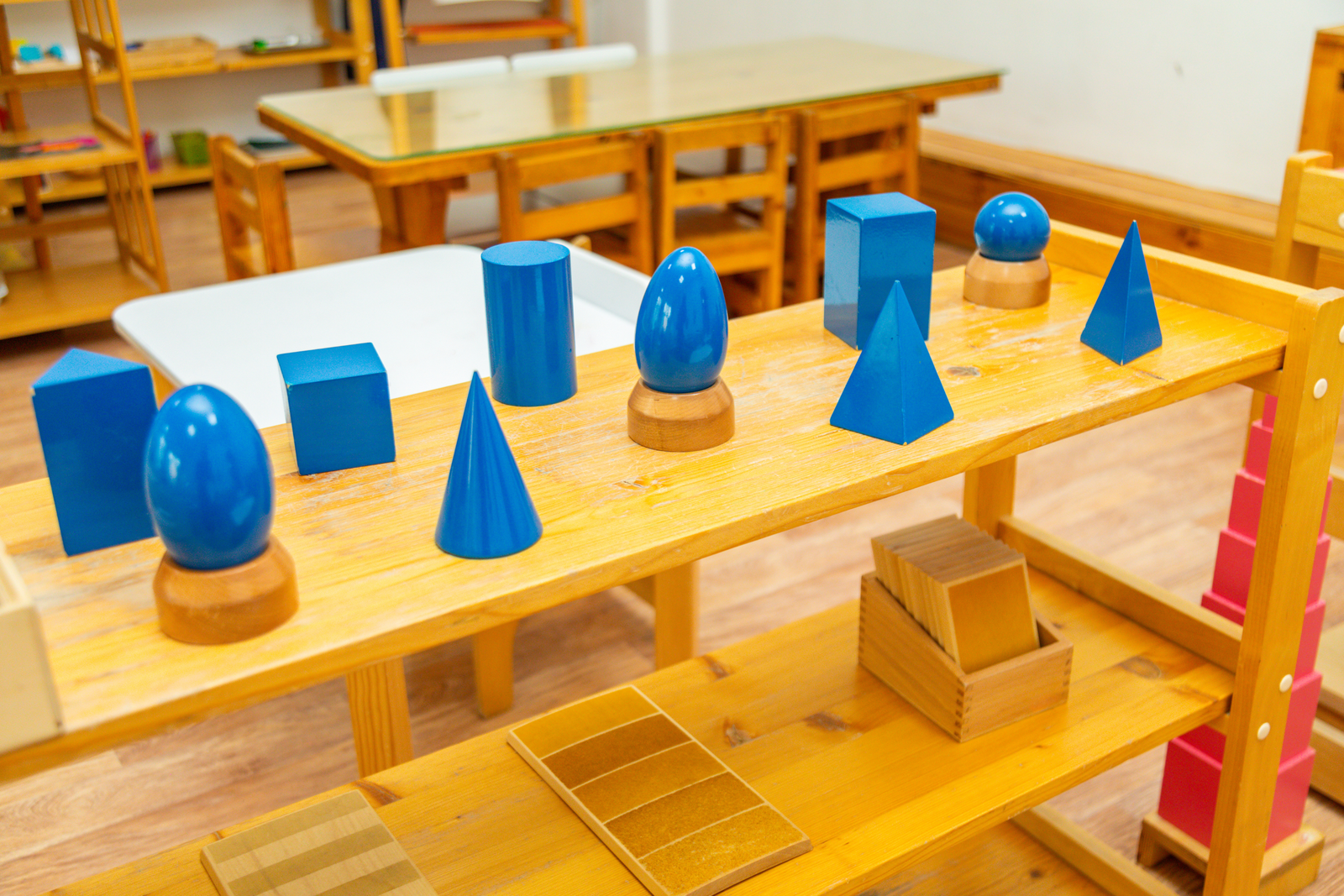 Full Montessori classroom shelf with geometric and sensorial materials