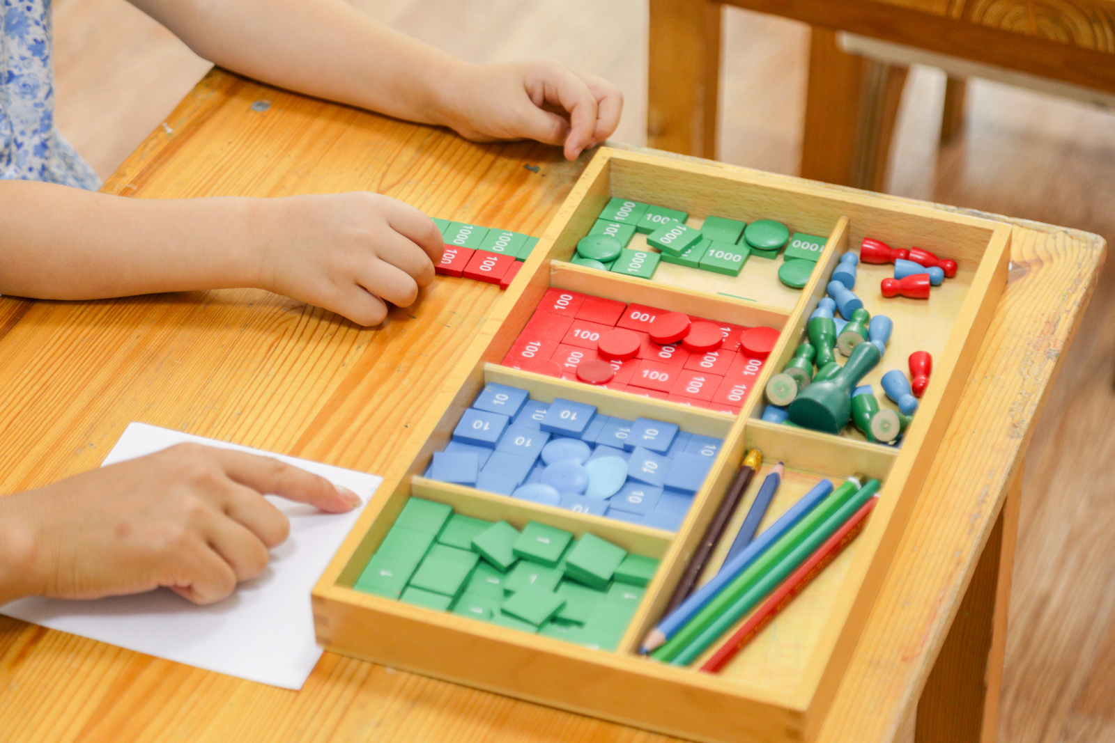 Child and adult using place-value math tiles together